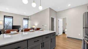 A modern kitchen with a large island, dark cabinets, and pendant lighting. - Across from Clinic | 2 Bed/2 Bath | Free Garage (Cleveland)