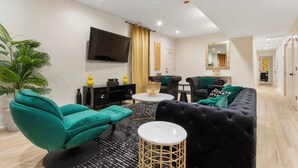 A modern living room with a sofa, armchair, coffee table, and a TV mounted on the wall.