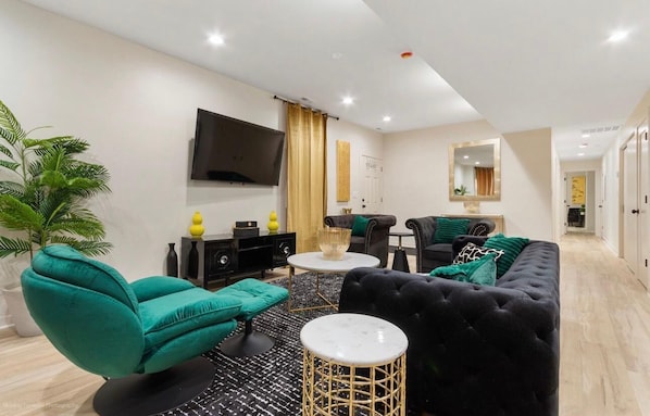 A modern living room with a sofa, armchair, coffee table, and a TV mounted on the wall. - Modern 3BR Apt Near United Center (Chicago)