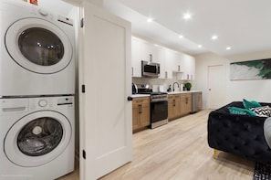 A compact kitchen with white cabinets, a microwave, and a stove. - Modern 3BR Apt Near United Center (Chicago)