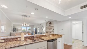 Una cocina moderna con encimeras de granito, armarios blancos y electrodomésticos de acero inoxidable.