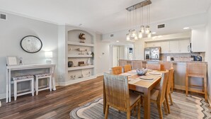 Una cocina moderna con armarios blancos, horno empotrado y refrigerador de acero inoxidable.