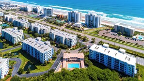 A high-rise hotel with multiple floors, a swimming pool, and a beachfront view. - "Passing Time" Condo Retreat | 3 Beds | 2 Baths | Slps 7 | Resort Amenities | Steps to the Beach (New Smyrna Beach)