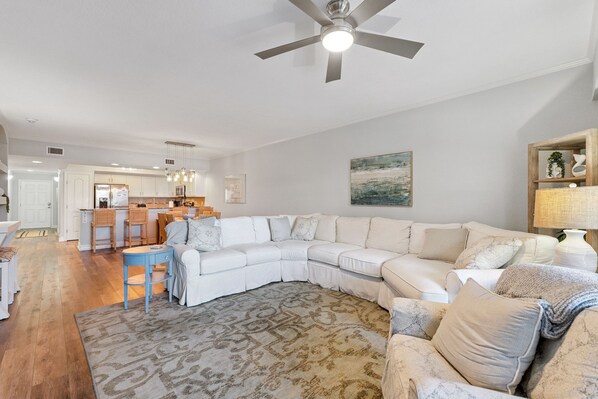 A spacious living room with a large sectional sofa, a coffee table, and a patterned rug. - "Passing Time" Condo Retreat | 3 Beds | 2 Baths | Slps 7 | Resort Amenities | Steps to the Beach (New Smyrna Beach)