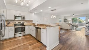 Una cocina moderna con armarios blancos, electrodomésticos de acero inoxidable y una isla central.