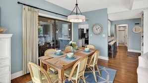 Un coin repas avec une table en bois, des chaises en osier et un lustre.