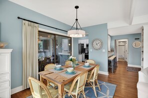 A dining area with a wooden table, wicker chairs, and a chandelier. - Discover Kiawah at 4922 Turtle Point, a stunning 3-bedroom with golf views! (Kiawah Island)