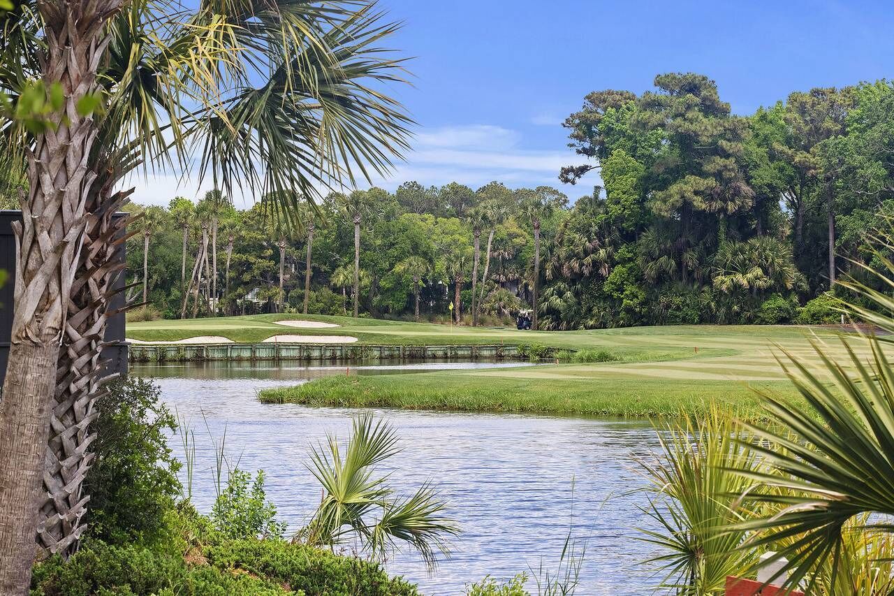 Ein Golfplatz mit Teich, umgeben von dichten Bäumen und Palmen.