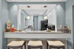 A kitchen with a central island, pendant lights, and a view into the adjacent dining area. - Discover Kiawah at 4922 Turtle Point, a stunning 3-bedroom with golf views! (Kiawah Island)