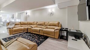 Uma sala de estar moderna com um amplo sofá em formato de L, uma mesinha de apoio e uma televisão de tela plana fixada na parede.
