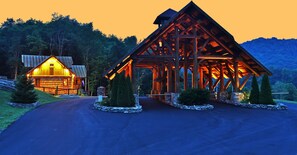 A wooden cabin with a sloped roof and a stone foundation, surrounded by a stone wall and small trees. - Black Diamond at Eagles Nest: Views, Hot Tub, Pet Friendly! (Banner Elk)