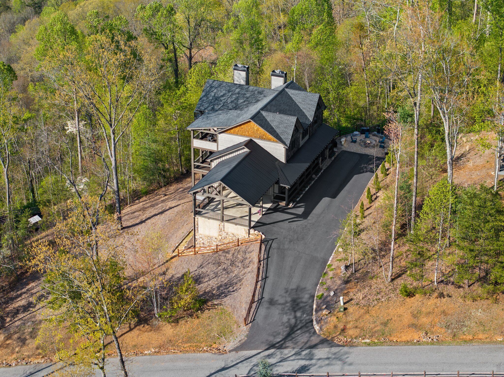 Un chalet à deux étages avec une façade en pierre, un porche couvert et une allée menant à l’entrée principale.