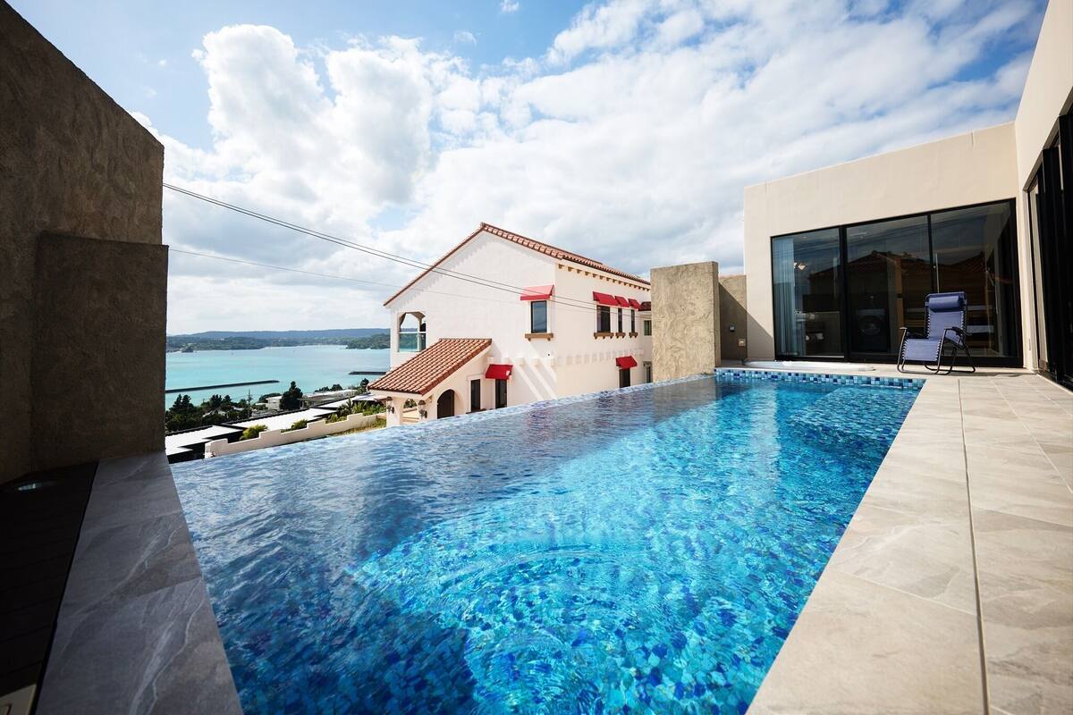 A swimming pool with a clear view of a building and a body of water in the background.