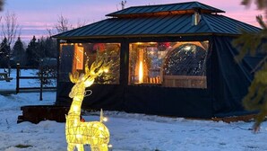 Uma cabana com telhado de metal e janelas amplas, rodeada por neve.
