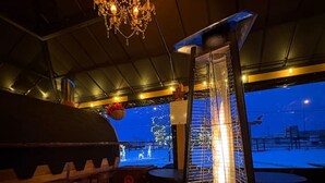 Uma área de bar com um banco alto, uma tela grande exibindo uma paisagem nevada e um lustre moderno.