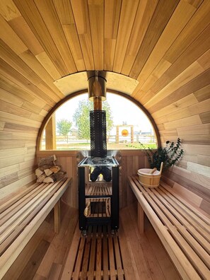 A sauna with a wooden interior, benches, and a visible chimney. - RV Apartment w/ Hyrdo-Spa (Stettler)