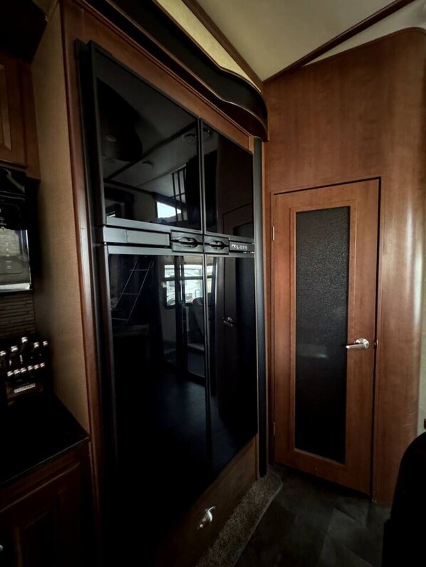 A room with a sliding door leading to a kitchen area. - RV Apartment w/ Hyrdo-Spa (Stettler)