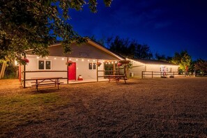 A building with a red door and two picnic tables in front.