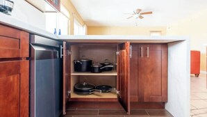 A compact kitchen with wooden cabinets, a built-in oven, and a ceiling fan. - Marvelous 3-bedroom house with AC in sunny Oceanside (Oceanside)