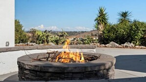 A stone fire pit with flames, surrounded by a white wall and a clear sky. - Marvelous 3-bedroom house with AC in sunny Oceanside (Oceanside)