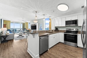 A modern kitchen with white cabinets, stainless steel appliances, and a large island. - Fall Deals + Snowbird Rates | Gulf Front Beach Escape (Panama City Beach)