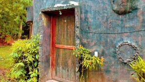A rustic building with a wooden door, a small porch, and a stone wall. - Puerto Quito Lodge - Mon Par (Puerto Quito)