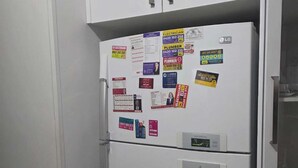 A white refrigerator with multiple magnets and notes, a digital display, and a water dispenser.