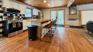 Una cocina moderna con vigas de madera en el techo, electrodomésticos de acero inoxidable y una barra con taburetes.