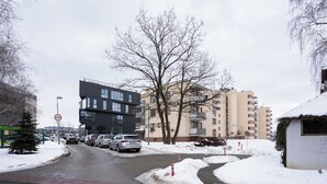 Una calle urbana nevada con coches estacionados, un paso de peatones y edificios residenciales de varios pisos.