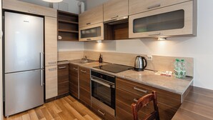Una cocina moderna con armarios de madera, un refrigerador de acero inoxidable, un horno y un microondas integrado.