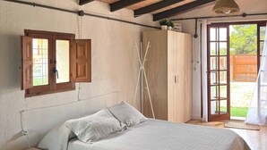Un dormitorio con cama, armario de madera y ventana con cortinas.