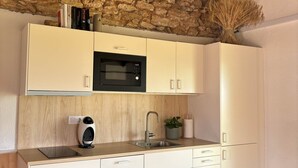 Una cocina moderna con armarios blancos, horno empotrado, microondas y pileta.