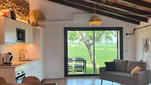 Una cocina moderna con armarios blancos, horno empotrado y zona de comedor con mesa y sillas de madera.