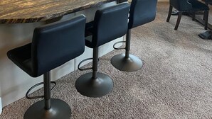 Una cocina moderna con encimera de granito, electrodomésticos de acero inoxidable y una zona de bar con taburetes.