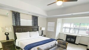 A bedroom with a bed, a chair, a ceiling fan, and a window with blinds. - Cozy 1-bedroom apartment in perfect Mandeville with AC and gym access (Mandeville)