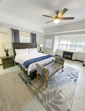 A bedroom with a bed, a chair, a ceiling fan, and a window with blinds. - Cozy 1-bedroom apartment in perfect Mandeville with AC and gym access (Mandeville)