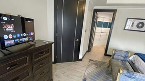 A modern bedroom with a bed, dresser, and TV. - Cozy 1-bedroom apartment in perfect Mandeville with AC and gym access (Mandeville)