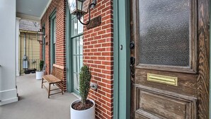 A brick building with a wooden door, a bench, and a potted plant.