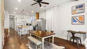A modern kitchen with white cabinets, a wooden island, and stainless steel appliances.