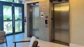 A modern lobby with two elevators, a reception desk, and a seating area.