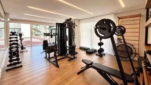 A modern gym with various exercise equipment, including dumbbells, a bench, and weight machines.