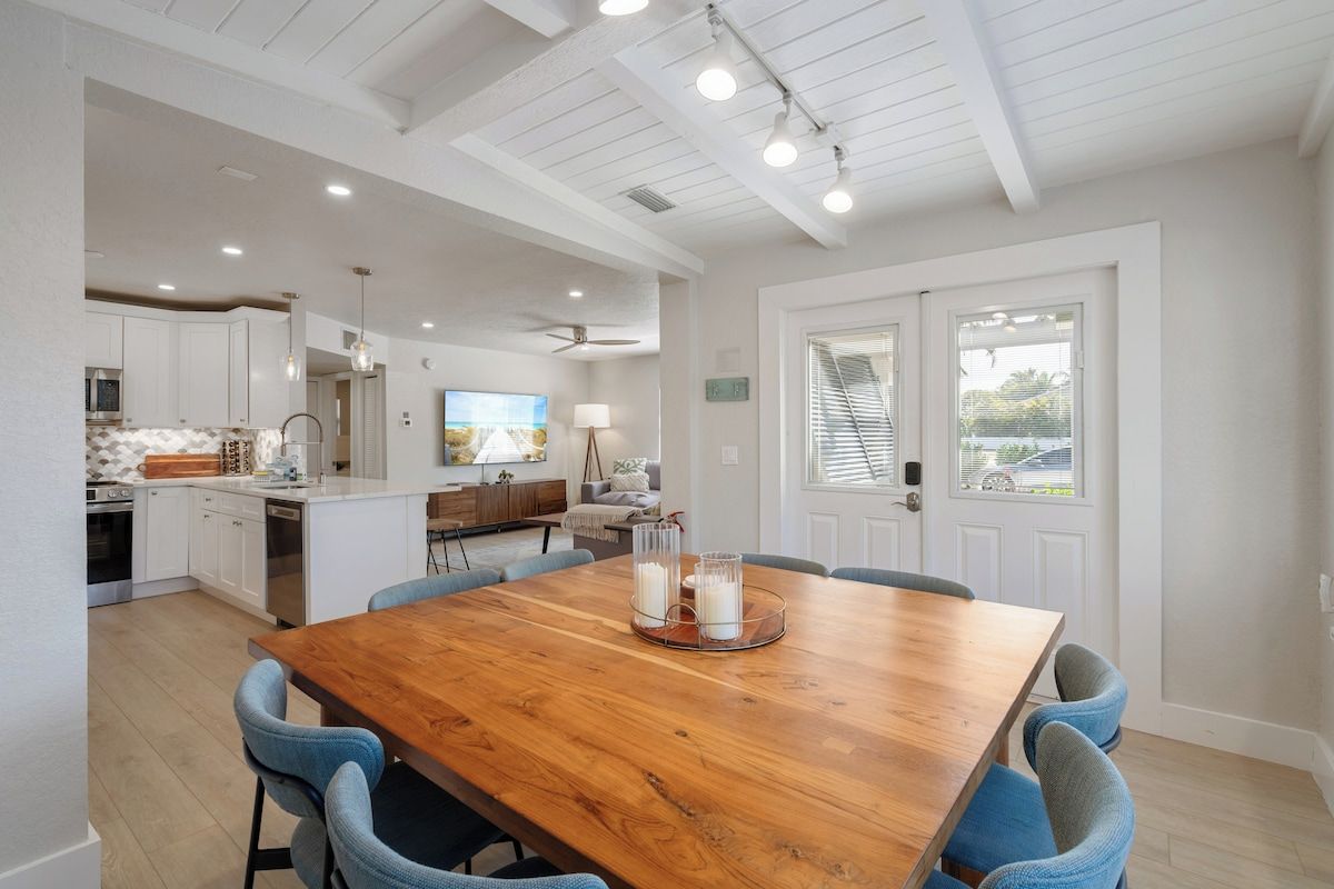 A spacious kitchen with white cabinetry, a wooden dining table with chairs, and a ceiling fan.