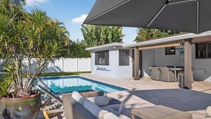 A pool area with lounge chairs and a covered patio. - Bliss - Tropical Paradise with Heated Pool (Wilton Manors)
