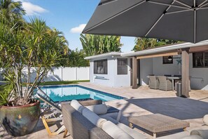 A pool area with lounge chairs and a covered patio. - Bliss - Tropical Paradise with Heated Pool (Wilton Manors)