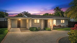A two-story house with a stone facade, a front porch, and a driveway. - Bliss - Tropical Paradise with Heated Pool (Wilton Manors)