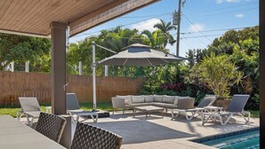 A covered outdoor patio with a pool, lounge chairs, and a sofa. - Bliss - Tropical Paradise with Heated Pool (Wilton Manors)