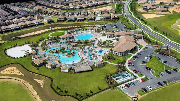 An aerial view of a residential area with multiple swimming pools, a parking lot, and a golf course. - Epic 8BR Escape: Themed Rooms, Home Cinema & Pool/Spa (Davenport)