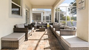 A covered outdoor seating area with wicker furniture and a poolside view. - Epic 8BR Escape: Themed Rooms, Home Cinema & Pool/Spa (Davenport)