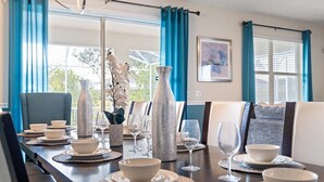 A dining area with a long table set for six, featuring white bowls, wine glasses, and decorative vases. - Epic 8BR Escape: Themed Rooms, Home Cinema & Pool/Spa (Davenport)