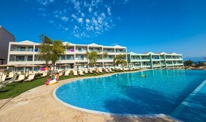 A hotel with a large swimming pool, multiple balconies, and sun loungers. - Robolla Beach (Corfu)